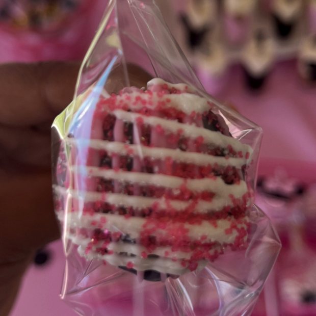 Chocolate-covered Oreo with white drizzle and pink sprinkles